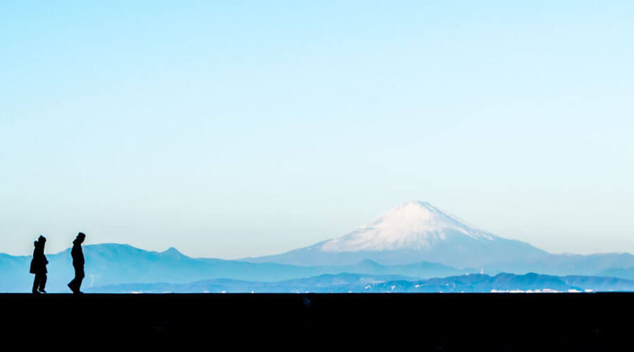 富士山を見ながら歩く二人の画像